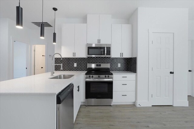 kitchen featuring kitchen peninsula, pendant lighting, white cabinets, and stainless steel appliances