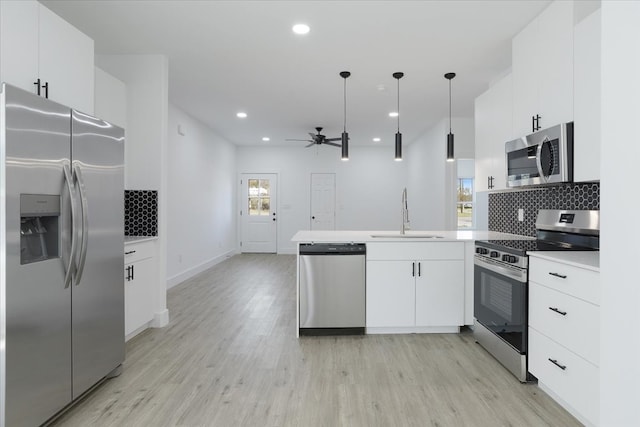 kitchen with pendant lighting, sink, ceiling fan, appliances with stainless steel finishes, and kitchen peninsula