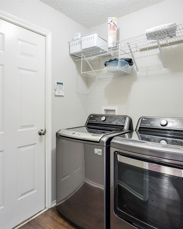 laundry room featuring a textured ceiling, dark hardwood / wood-style floors, and washer and clothes dryer