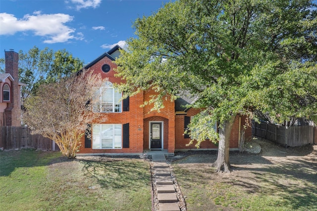 view of front of house featuring brick siding, a front yard, and fence