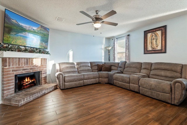 living room with ceiling fan, a fireplace, and a textured ceiling