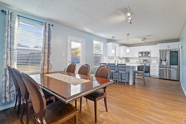 dining area featuring light hardwood / wood-style flooring and a textured ceiling