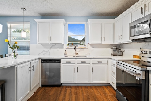 kitchen with white cabinetry, appliances with stainless steel finishes, kitchen peninsula, and sink