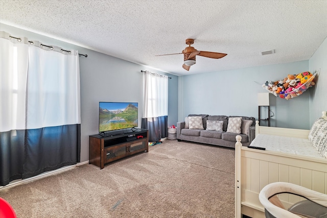 living room featuring ceiling fan, carpet floors, and a textured ceiling