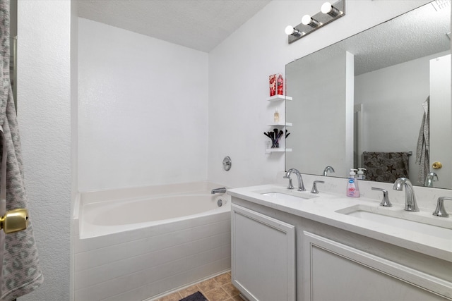 bathroom featuring vanity, tiled bath, and a textured ceiling