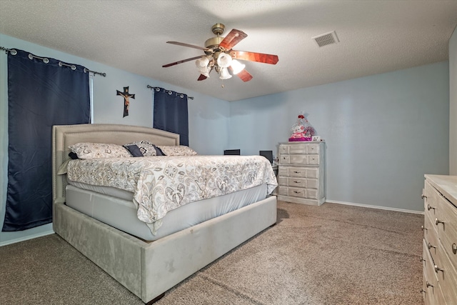 bedroom with ceiling fan, carpet floors, and a textured ceiling