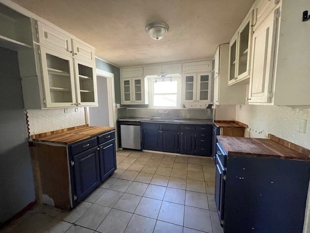 kitchen featuring butcher block countertops, dishwasher, white cabinetry, and blue cabinets