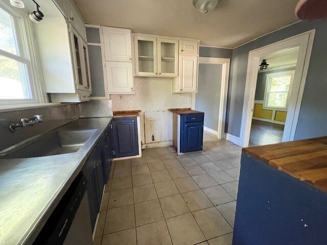 kitchen featuring white cabinets, sink, butcher block counters, and blue cabinetry