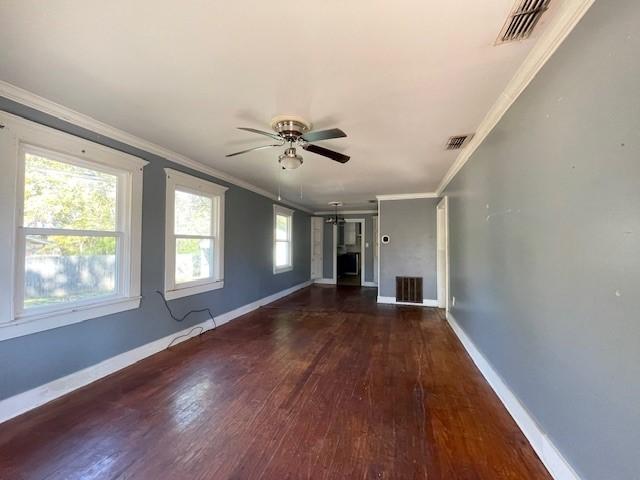 unfurnished living room with plenty of natural light, ornamental molding, and dark wood-type flooring