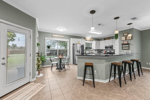 kitchen with kitchen peninsula, a kitchen breakfast bar, stainless steel appliances, pendant lighting, and white cabinets