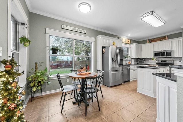 kitchen featuring tasteful backsplash, stainless steel appliances, crown molding, white cabinetry, and light tile patterned flooring