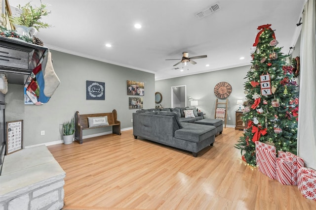 living room with light hardwood / wood-style flooring, ceiling fan, and crown molding