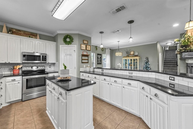 kitchen featuring a kitchen island, white cabinetry, stainless steel appliances, and hanging light fixtures