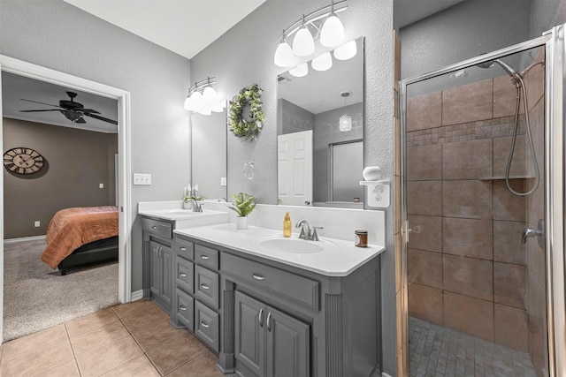 bathroom with tile patterned flooring, ceiling fan, a tile shower, and vanity