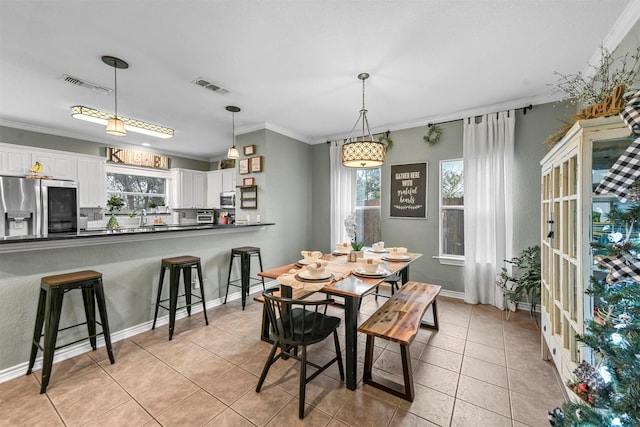 tiled dining room with ornamental molding and sink