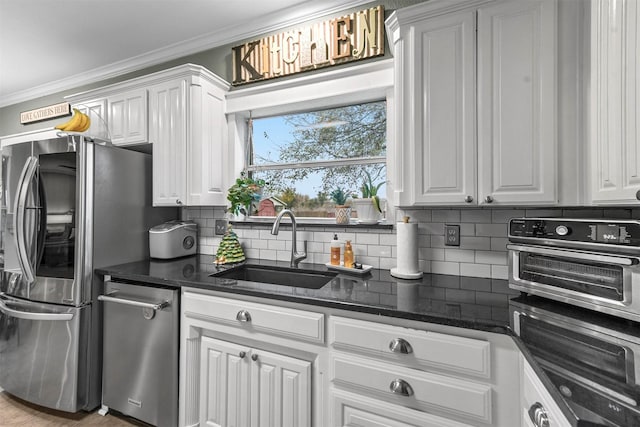 kitchen featuring crown molding, sink, white cabinets, and dark stone counters