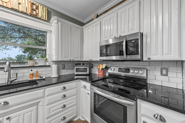 kitchen featuring dark stone countertops, white cabinetry, stainless steel appliances, and ornamental molding