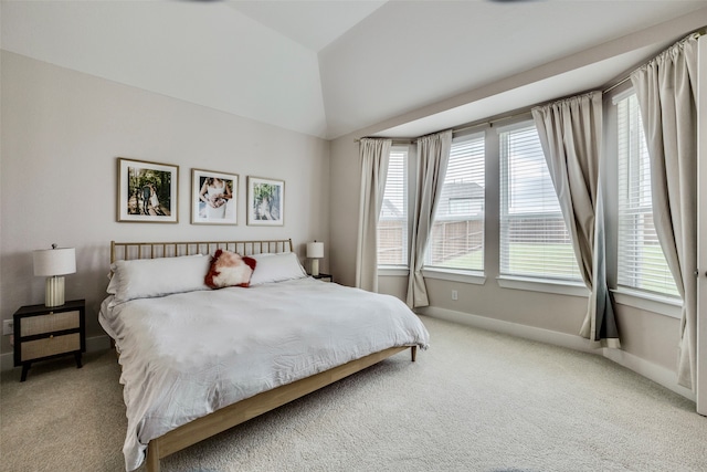 bedroom with multiple windows, light colored carpet, and vaulted ceiling