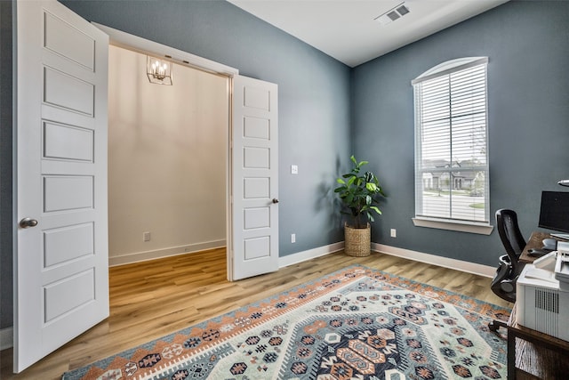 office with wood-type flooring and an inviting chandelier