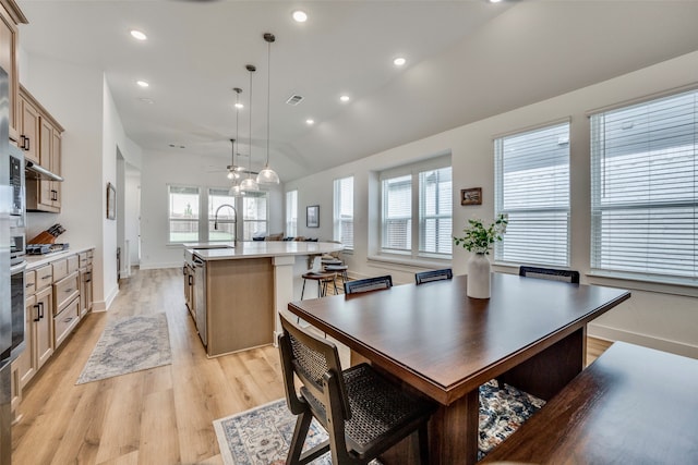 dining area with plenty of natural light, light wood-type flooring, lofted ceiling, and sink