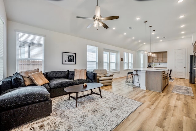 living room featuring light wood-type flooring, ceiling fan, lofted ceiling, and sink