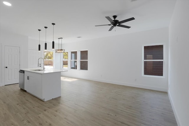 kitchen with sink, light hardwood / wood-style flooring, an island with sink, decorative light fixtures, and white cabinets