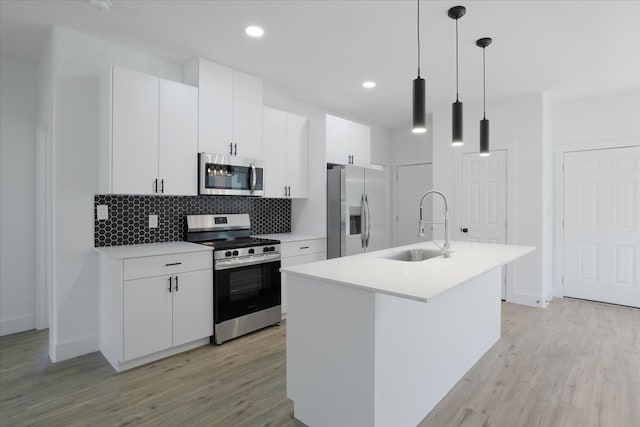 kitchen with white cabinetry, sink, stainless steel appliances, and decorative light fixtures