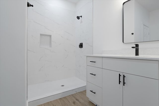 bathroom featuring hardwood / wood-style flooring, vanity, and a tile shower