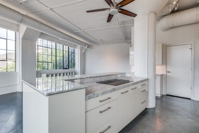 kitchen with light stone counters, black electric cooktop, ceiling fan, white cabinets, and a kitchen island