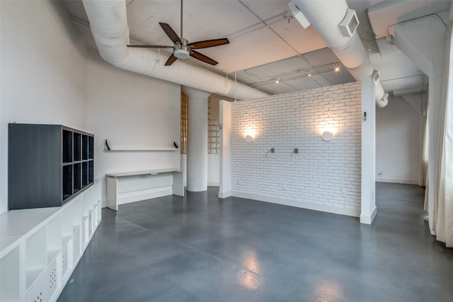 unfurnished living room featuring ceiling fan and brick wall