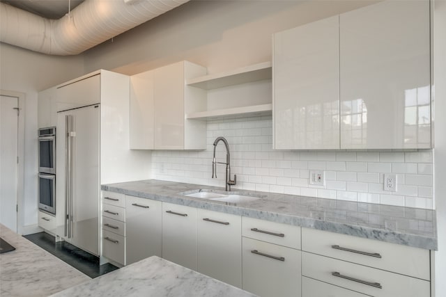 kitchen featuring white cabinetry, sink, light stone counters, dark hardwood / wood-style floors, and backsplash