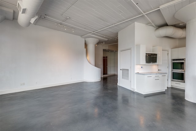 unfurnished living room featuring a towering ceiling