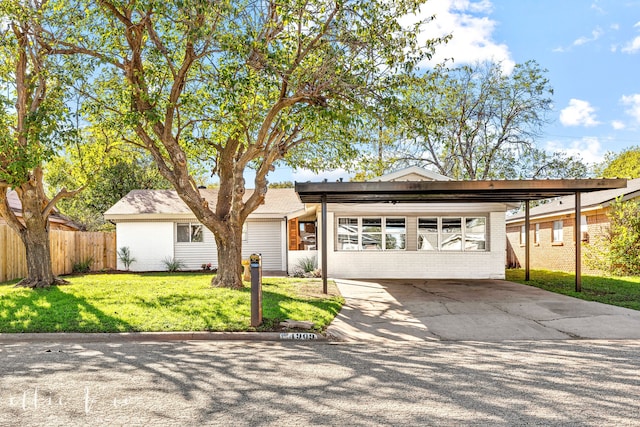 ranch-style home featuring concrete driveway, brick siding, a front yard, and fence