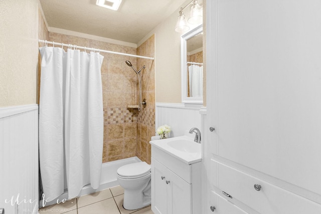 bathroom with wainscoting, a tile shower, vanity, and tile patterned floors