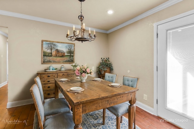 dining room with hardwood / wood-style flooring, ornamental molding, and an inviting chandelier