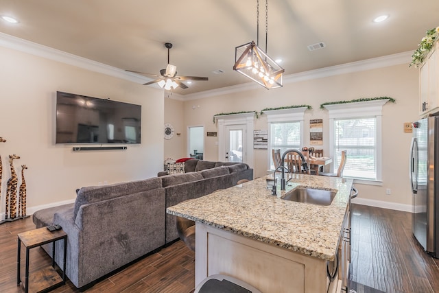 kitchen with light stone countertops, stainless steel fridge, sink, dark hardwood / wood-style floors, and an island with sink