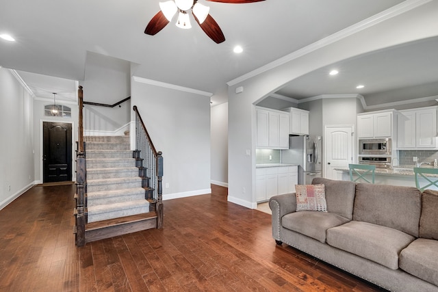 living room with ornamental molding, ceiling fan, and dark wood-type flooring