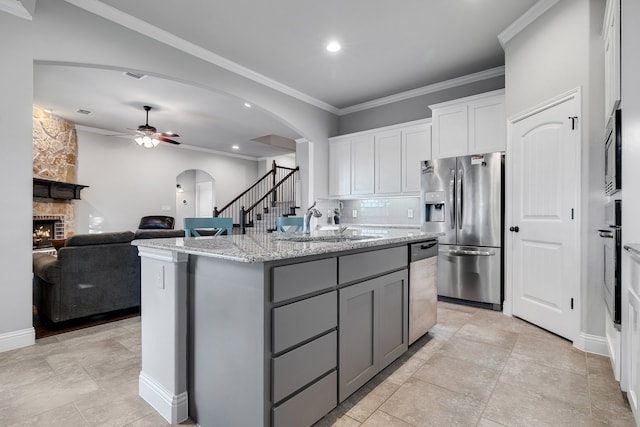 kitchen featuring stainless steel appliances, white cabinetry, a center island with sink, and crown molding