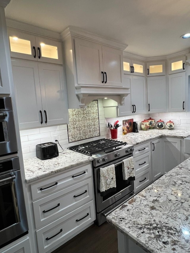 208 Cedar Ln, Burleson, TX 76028 - kitchen featuring stainless steel range with gas stovetop, light stone countertops, white cabinetry, and tasteful backsplash