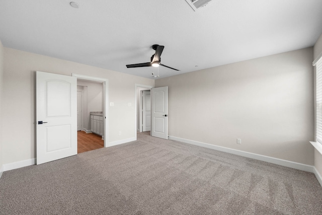 unfurnished bedroom with connected bathroom, light colored carpet, and ceiling fan