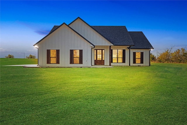 back house at dusk featuring a yard