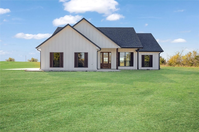 rear view of house with board and batten siding, a shingled roof, and a yard