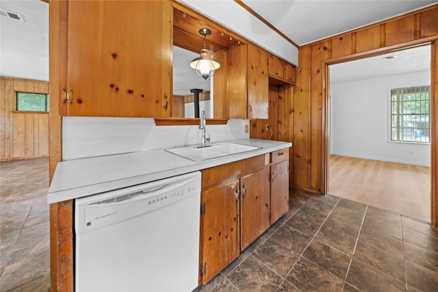 kitchen with wood walls, white dishwasher, sink, decorative light fixtures, and dark hardwood / wood-style flooring