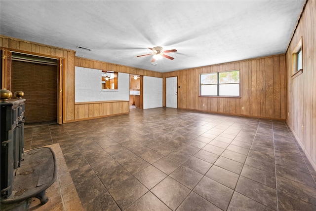 unfurnished living room with ceiling fan and wood walls