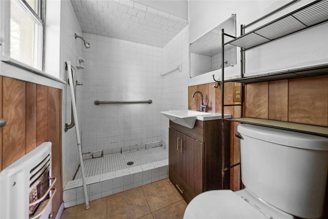 bathroom featuring tile patterned flooring, a tile shower, vanity, and toilet