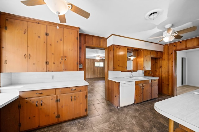 kitchen featuring dishwasher, wooden walls, and sink