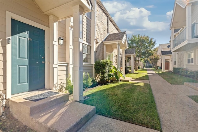 view of exterior entry featuring a lawn