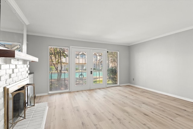 unfurnished living room featuring a fireplace, french doors, ornamental molding, and light hardwood / wood-style flooring