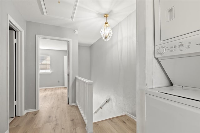 hallway with stacked washer and dryer and light wood-type flooring