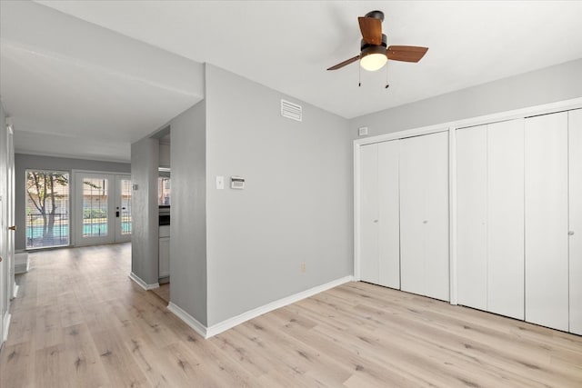 unfurnished bedroom featuring light hardwood / wood-style floors, ceiling fan, and multiple closets